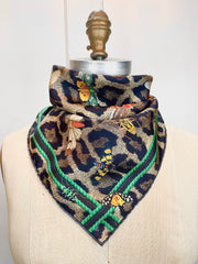 A designer silk bandana wrapped around the neck of a form. The Italian silk bandana Features a Leopard fur print, adorned with multicolored entomological moths, butterflies, beetles, and dragonflies and framed by a rope ribbon border. Imagined to be a sleeping Leopard, where butterflies and the such come to land and rest on her back in a daydream...  This is a hand sewn silk scarf.