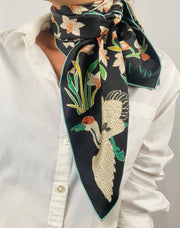 Classic woman wearing bespoke Elwyn New York Scarf tied around her neck with a botanical crane print is collaged together from antique glass and pearl, beaded embroideries of yesteryear.