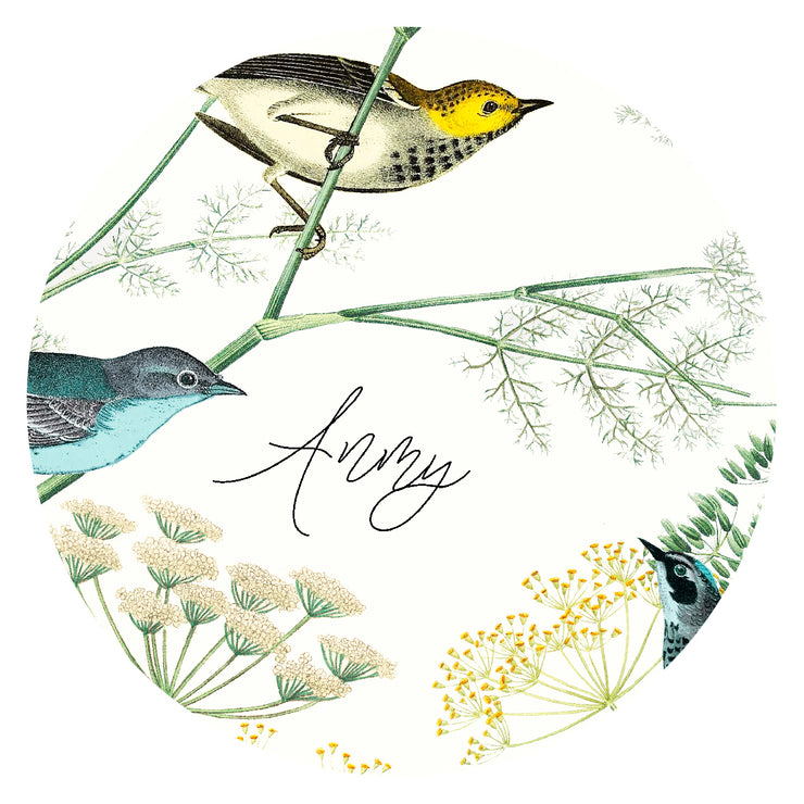 round, closeup illustration of a bespoke Elwyn New York silk scarf with a Charming blue and yellow warbler birds, flying and perched amidst delicate wild flowers. Inspired by nature found in the North East with an example of customer's name inscribed in the print.