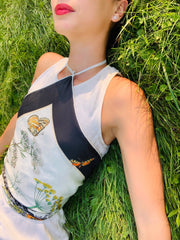 Classic woman laying in a field, wearing a luxury, bespoke Elwyn New York silk scarf tied around her torso with a vintage style, botanical, floral, butterfly and leopard print