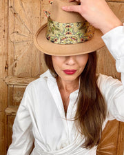 A model wearing a wrap top and Italian silk bandana with a geometric butterfly print tied around her hat. 