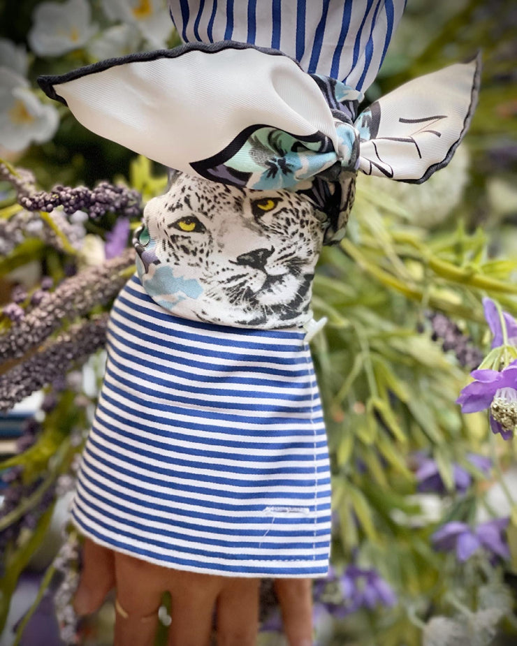closeup of a bespoke Elwyn New York silk bandana, tied around the cuff of a sleeve with a vintage style print of a bluish floral field and modern lazing leopards