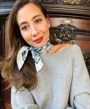 model wearing a cozy cashmere sweater and a  bespoke Elwyn New York silk bandana, tied around her neck with vintage style print of a bluish floral field and modern lazing leopards