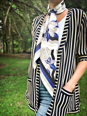 A classic woman surrounded by trees, wearing a bespoke, luxury elwyn new york scarf draped loose and long around her neck. This Denim friendly, zig-zag, art deco floral print feels modern and graphic.