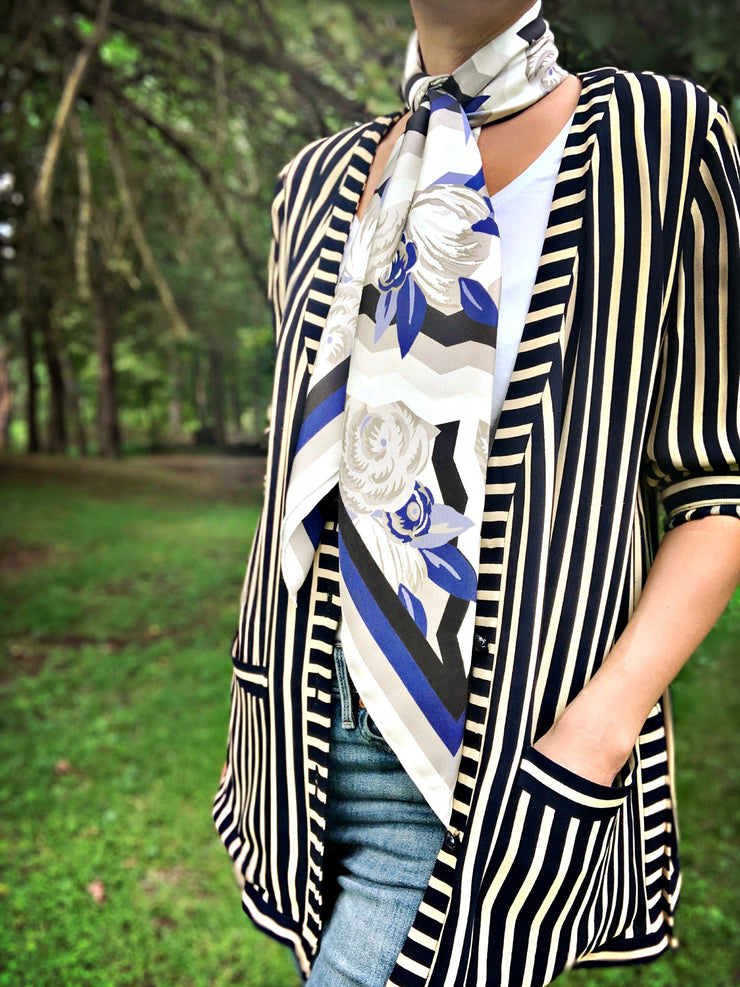 A classic woman wearing a bespoke, luxury elwyn new york scarf draped loose and long around her neck. This Denim friendly, zig-zag, art deco floral print feels modern and graphic.