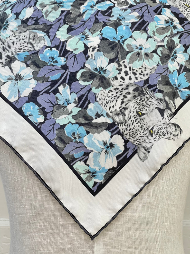 closeup corner of a bespoke Elwyn New York silk bandana, draped on the back of a form with vintage style print of a bluish floral field and modern lazing leopards