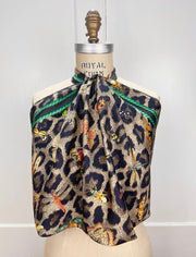 A designer silk scarf tied around the neck of a form like a halter top. The Italian silk scarf Features a Leopard fur print, adorned with multicolored entomological moths, butterflies, beetles, and dragonflies and framed by a rope ribbon border. Imagined to be a sleeping Leopard, where butterflies and the such come to land and rest on her back in a daydream... This is a hand Sewn Silk Scarf