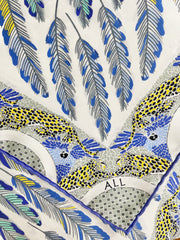 closeup picture of a personalized bespoke Elwyn New York silk scarf with a delightful design of swirling feathers, surrounded by creeping jaguars and parrots in the graphic border and an example of customer initials.
