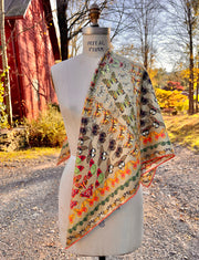 An Italian silk scarf featuring a geometric design, mixing earth tones and pops of brightly colored etymological butterflies laid across a dress form's shoulder.