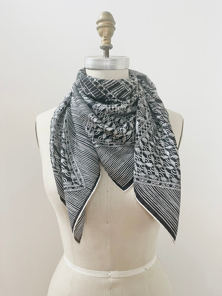 A luxury, bespoke, black and white Elwyn New York silk scarf wrapped around the neck of a form with vintage modern style graphic needlework and crochet print