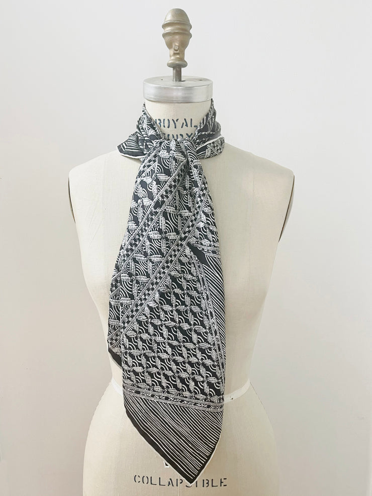 A luxury, bespoke, black and white Elwyn New York silk scarf knotted at the neck of a form with vintage modern style graphic needlework and crochet print