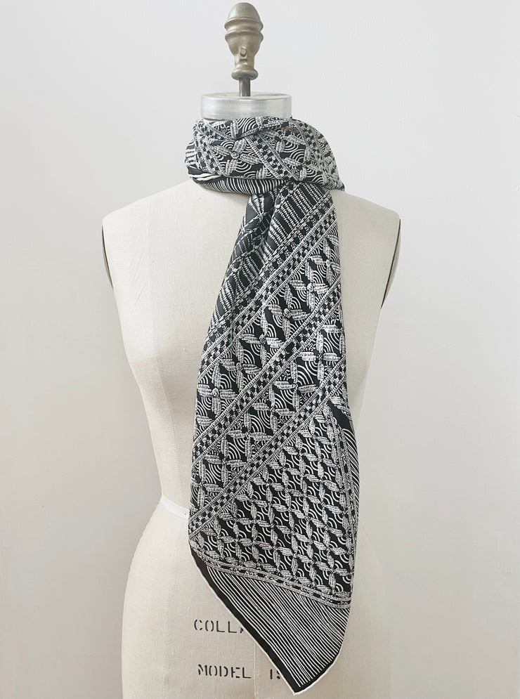 A luxury, bespoke, black and white Elwyn New York silk scarf wrapped around the neck of a form with vintage modern style graphic needlework and crochet print