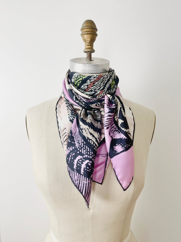 A luxury, bespoke Elwyn New York silk scarf tied around the neck of a form with a fierce tiger and pastel lavender, peach, green, black stripe print