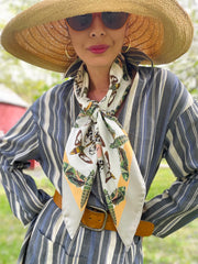 Front view of a classic woman, wearing a sunhat and luxury, bespoke Elwyn New York silk scarf around her neck with a geometric butterfly vintage modern style print