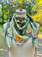 This bespoke, designer silk Scarf is Art Nouveau inspired featuring a kaleidoscope of fantastical flowers, butterflies and cockatoos rising from the curling foliage. The form is tied around a form in the woods. 