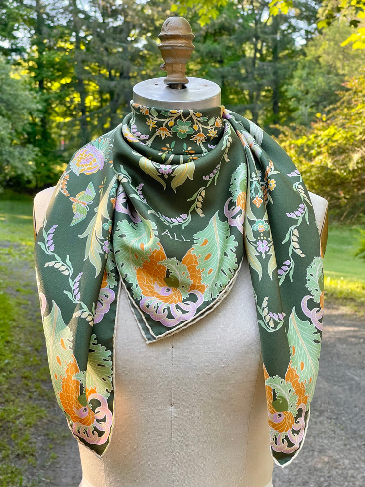 A dress form with an Italian silk scarf wrapped around the neck with an Art Nouveau print inspired featuring a kaleidoscope of fantastical flowers, butterflies and cockatoos rising from the curling foliage