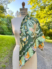 A dress form with an Italian silk scarf draped around it's shoulder with an Art Nouveau print inspired featuring a kaleidoscope of fantastical flowers, butterflies and cockatoos rising from the curling foliage