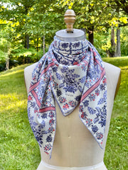 This bespoke, luxury Italian silk scarf is inspired by the lighthearted prints of the 18th Century.  The main pattern is made up of a red, white and blue diamond lattice of curving ribbons, enclosing sprays of flowers and is surrounded by an eyelet lace border, adorned with charming little birds. The ultimate feminine design.
