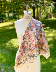 A dress form with a silk scarf around the shoulder that is rich with sunset colored wildflowers and energized leopards romping around the border. 