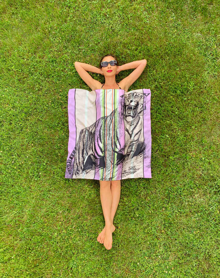 Bird's eye view of classic woman laying in the grass in a bikini with a luxury, bespoke Elwyn New York silk scarf covering her body which has a fierce tiger and pastel lavender, peach, green, black stripe print