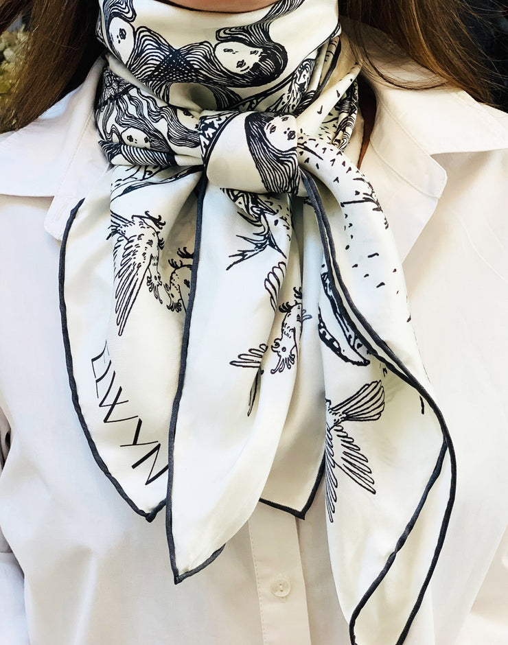 Front view of a Classic woman wearing a luxury, bespoke Elwyn New York silk scarf tied around her neck with black and white, art nouveau, whimsical, storybook print