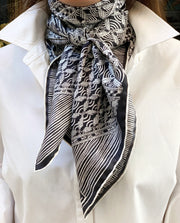 Classic woman wearing a luxury, bespoke, black and white Elwyn New York silk scarf tied around her neck with vintage modern style graphic needlework and crochet print