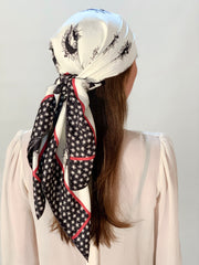 classic woman wearing a luxury, bespoke Elwyn New York silk scarf on her head with black and white, whimsical, polka dot, bird and stars, storybook print