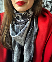classic female wearing a red coat and bespoke, luxury, black and white Elwyn New York silk scarf around her neck with vintage lace print and graphic fringe border
