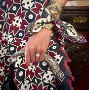 A model wearing a geometric skirt, holding a clutch, and Italian silk bandana with a geometric print wrapped around her wrist . 
