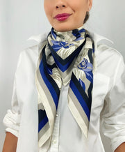 Front view of a classic woman wearing a bespoke, luxury elwyn new york scarf looped around her neck. This Denim friendly, zig-zag, art deco floral print feels modern and graphic.