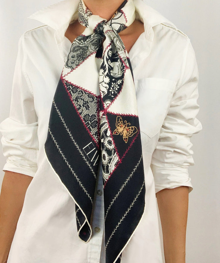 Classic woman wearing bespoke, luxury Elwyn New York silk scarf tied long around her neck. This geometric crazy quilt print is a vintage-modern depiction of the year 2020 filled with digital embroidery and lace of years past