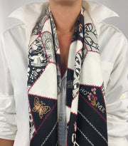 Classic woman wearing bespoke, luxury Elwyn New York silk scarf draped long and loose around her neck. This geometric crazy quilt print is a vintage-modern depiction of the year 2020 filled with digital embroidery and lace of years past. One can see the word HOME depicted in this photo