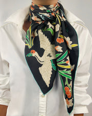 Classic woman wearing bespoke Elwyn New York Scarf tied around her neck with a botanical crane print is collaged together from antique glass and pearl, beaded embroideries of yesteryear.