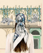 classic female traveler standing in front of a vintage garden Illustration, wearing a luxury, bespoke Elwyn New York silk scarf on her head with vintage style print of floral field and modern lazing leopards