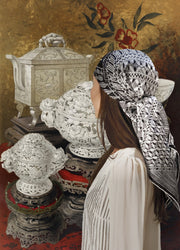 Classic Female standing in front of a intricate illustration of antique carved porcelain, wearing a luxury, bespoke, black and white Elwyn New York silk scarf on her head with vintage modern style graphic needlework and crochet print 