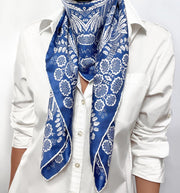 Woman wearing a bespoke Elwyn New York Scarf around her neck with an ornate, blue and white, vintage-pastoral bandana design. Classic, feminine, and romantic