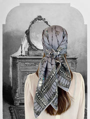 Fantasy Image: Back View of a Classic woman wearing a bespoke Elwyn New York silk scarf on her head with a vintage chain and beaded sautoir print that has intricate, little charm motifs that are strung together in long flowing chains. Woman Standing in front of an ornate Vanity illustration