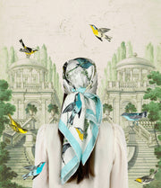 Garden vintage fantasy illustration of a back view of a woman wearing a bespoke Elwyn New York silk scarf around her head with a Charming blue and yellow warbler birds, flying and perched amidst delicate wild flowers. Inspired by nature found in the North East.