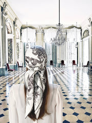 Fantasy photo of the back of a classic female standing in a light filled ballroom, wearing a luxury, bespoke Elwyn New Yorksilk scarf on her head with black and white, art nouveau, whimsical, storybook print
